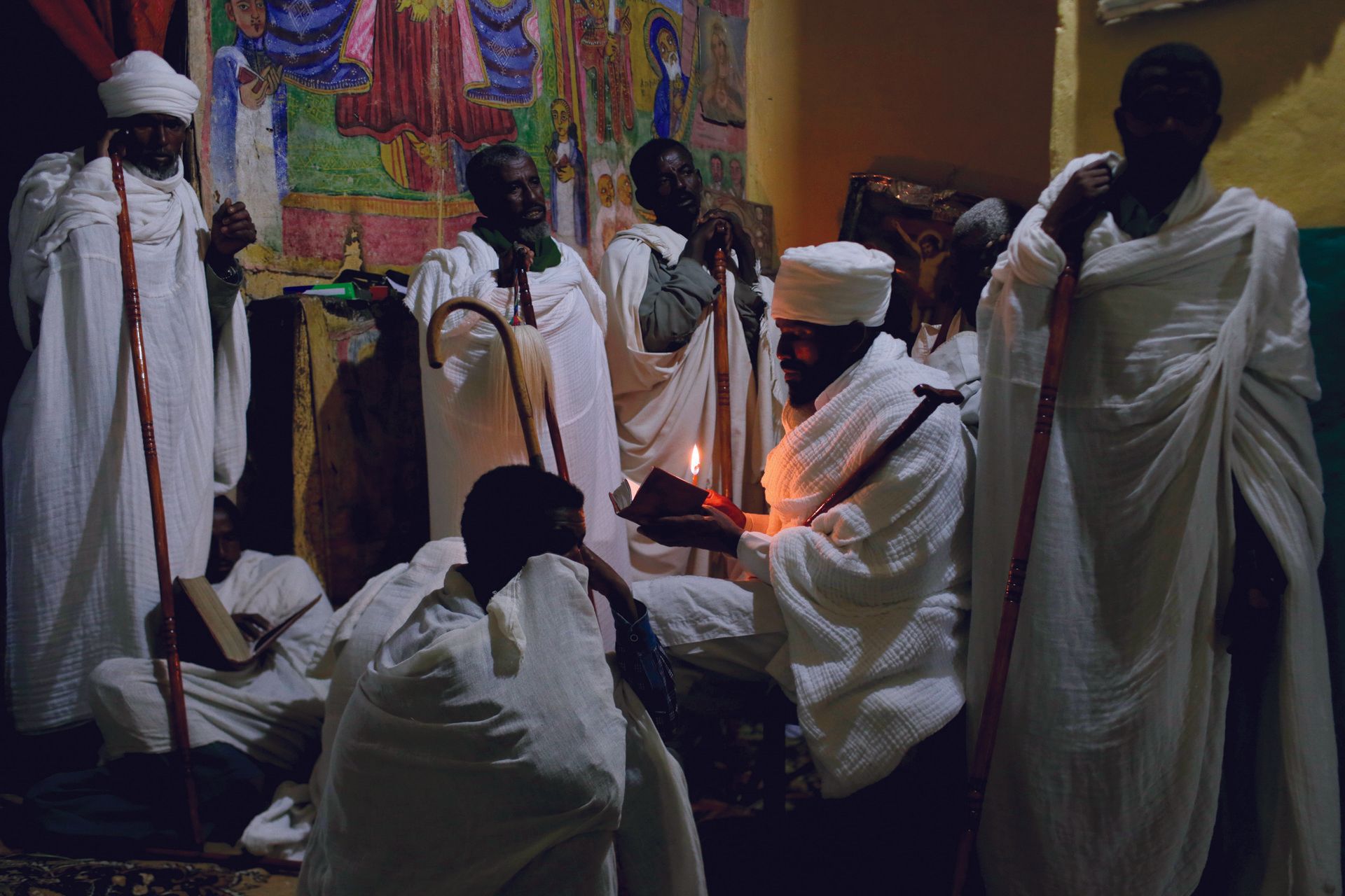 VII Foundation: Men in white gowns surrounding a man in the middle holding a book