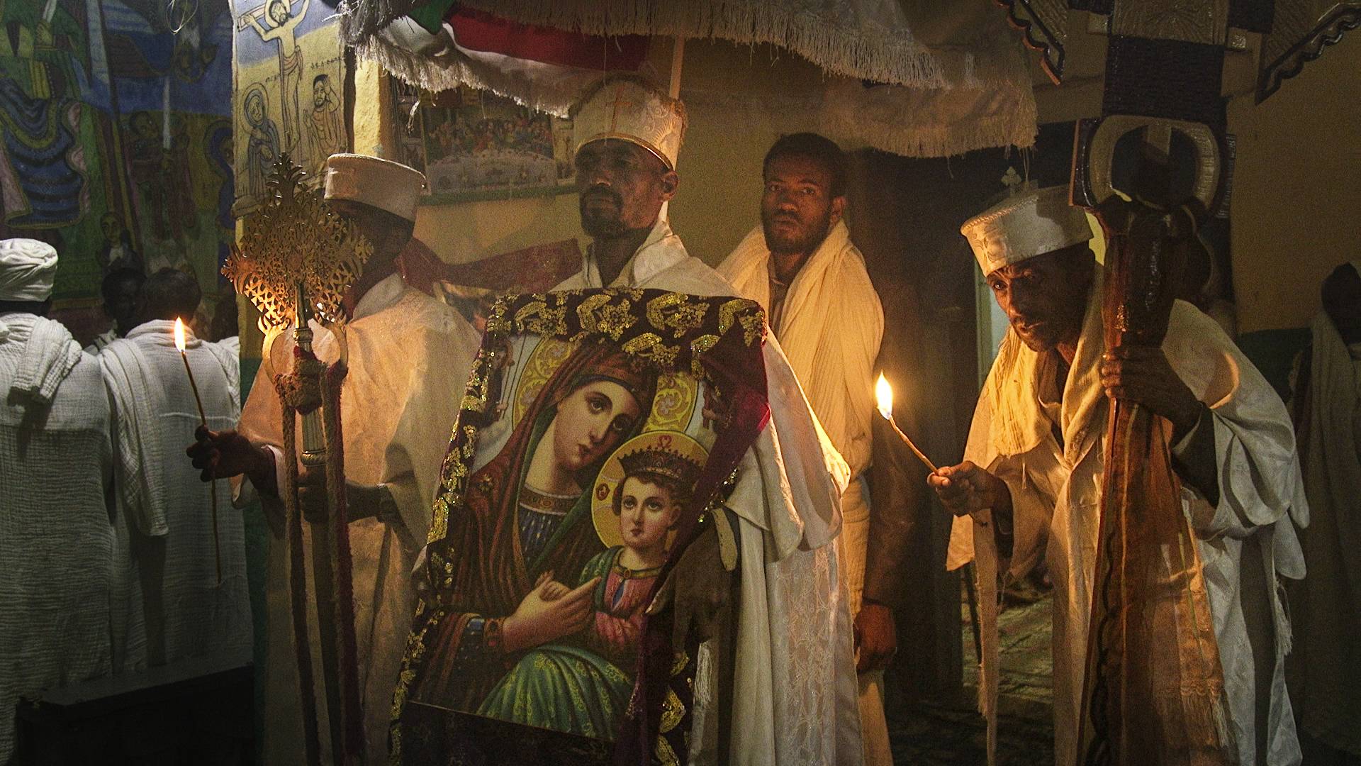 A group of people are standing around a painting of jesus and mary.