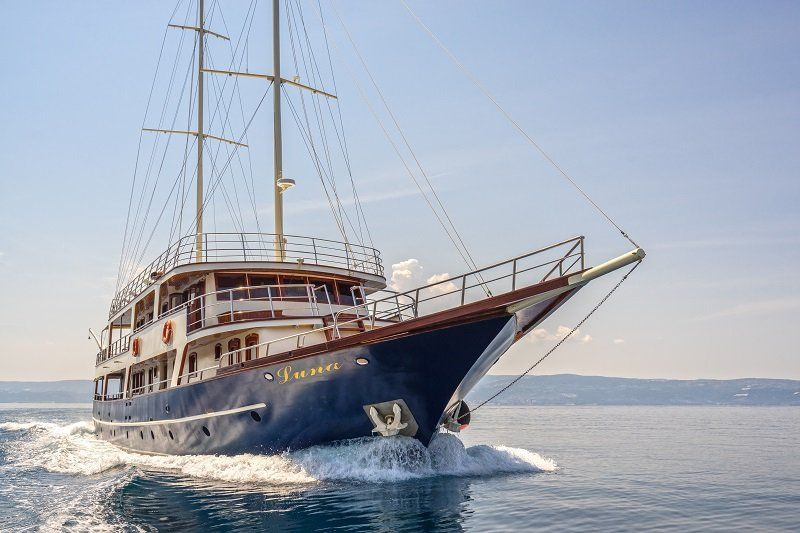 Een blauwe zeilboot vaart op een zonnige dag.