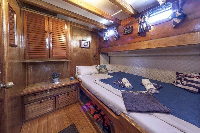 Gezellige hut met een tweepersoonsbed, houten wanden, een tafeltje en een opbergkastje.
