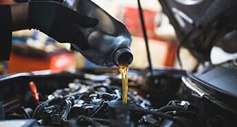 Man putting oil in the engine — Safety Inspection in West Chester, PA Man putting oil in the engine — Safety Inspection in West Chester, PA