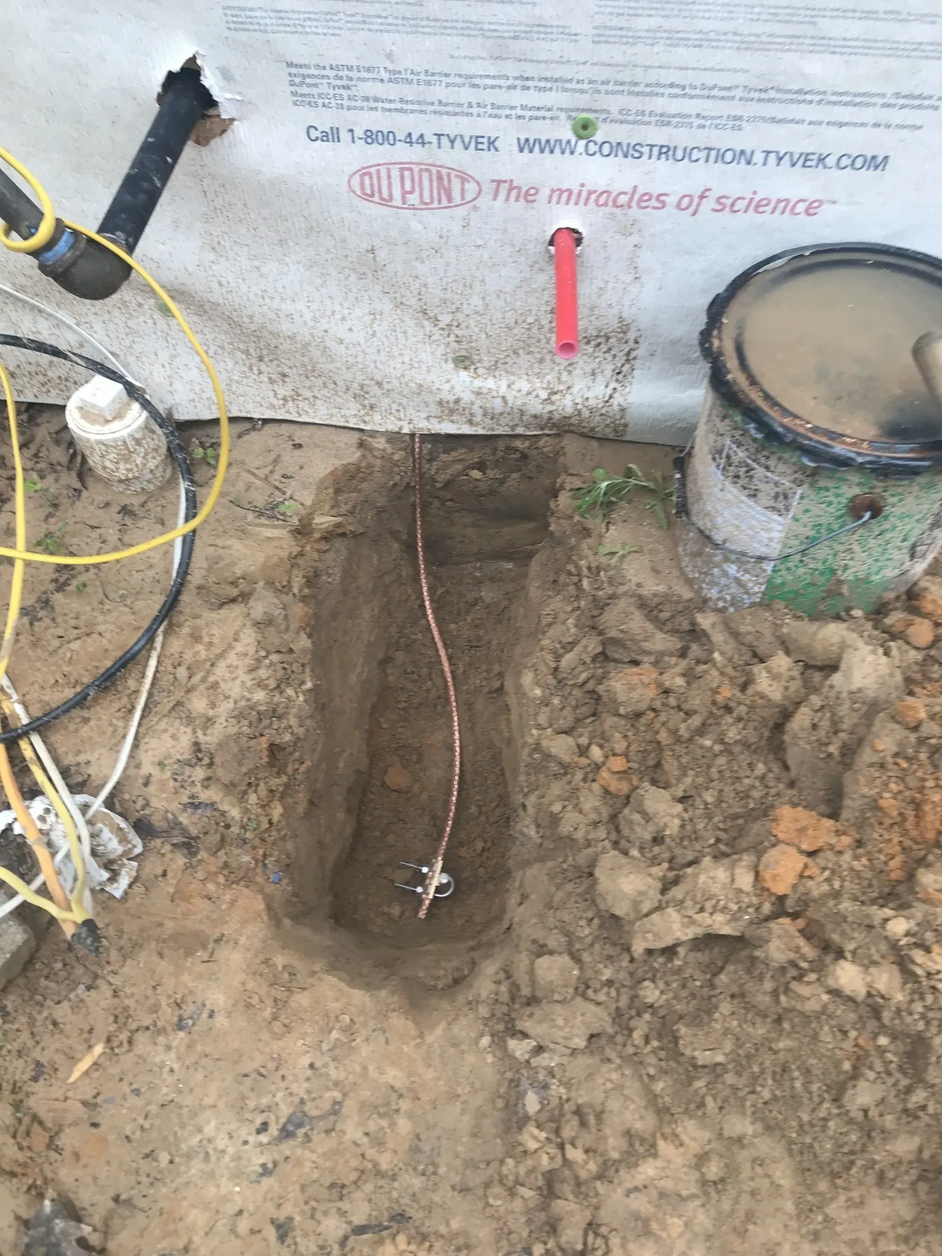 A hole in the ground with a copper wire sticking out of it.