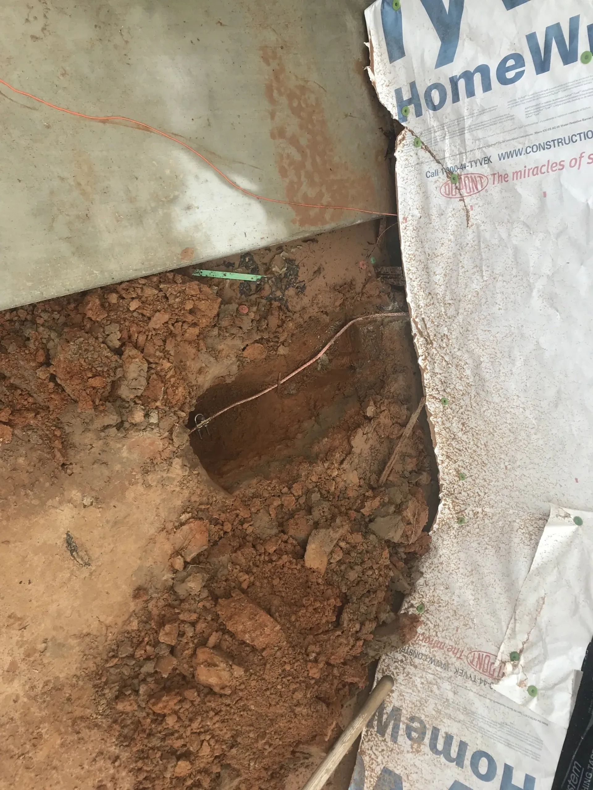 A close up of a hole in the ground next to a piece of cardboard.