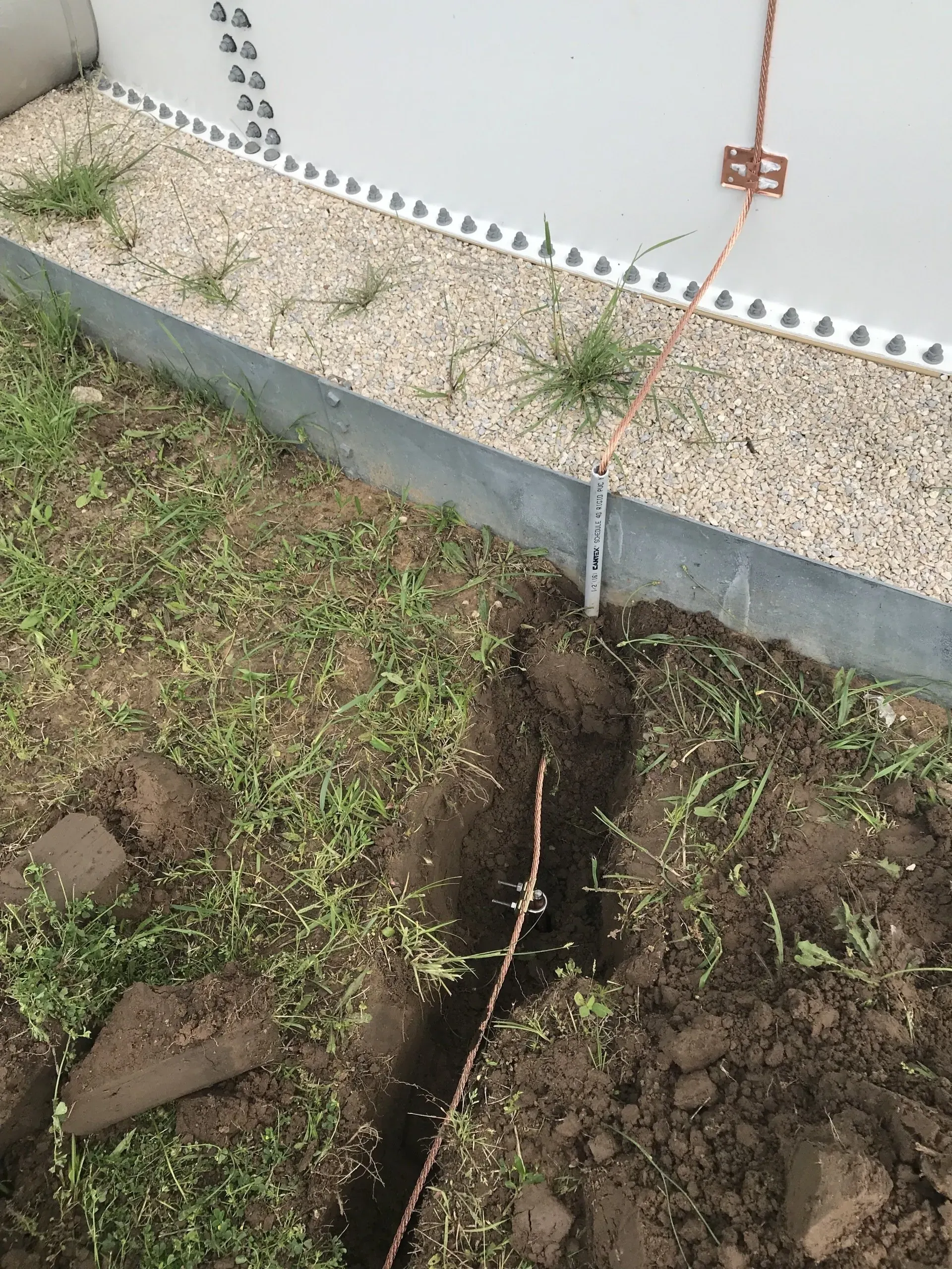 A hole in the ground with a copper wire sticking out of it.