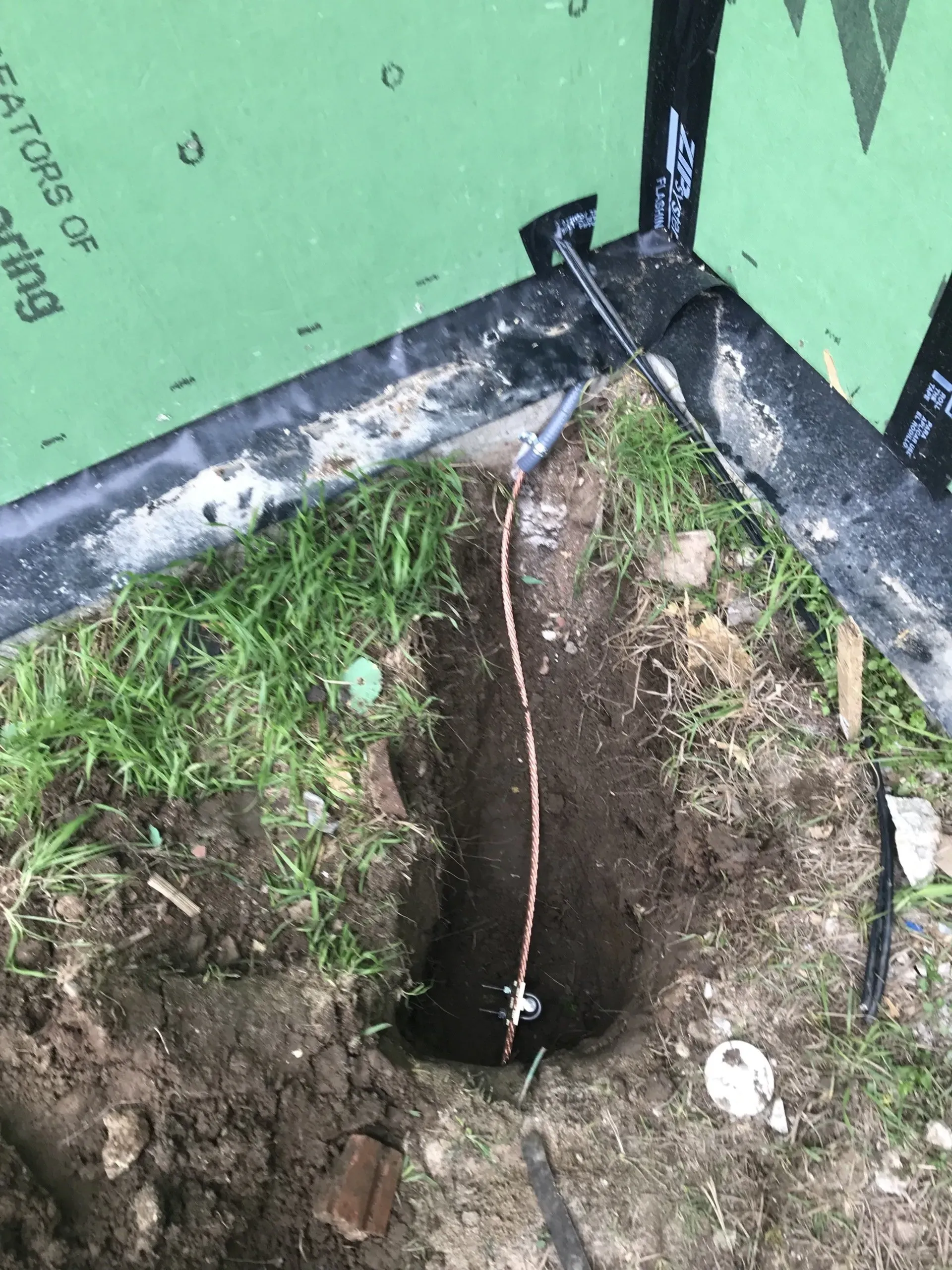 A hole in the ground with a copper wire sticking out of it