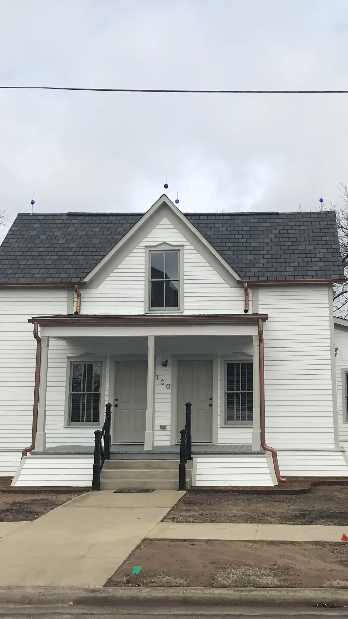 A white house with a gray roof and a porch.