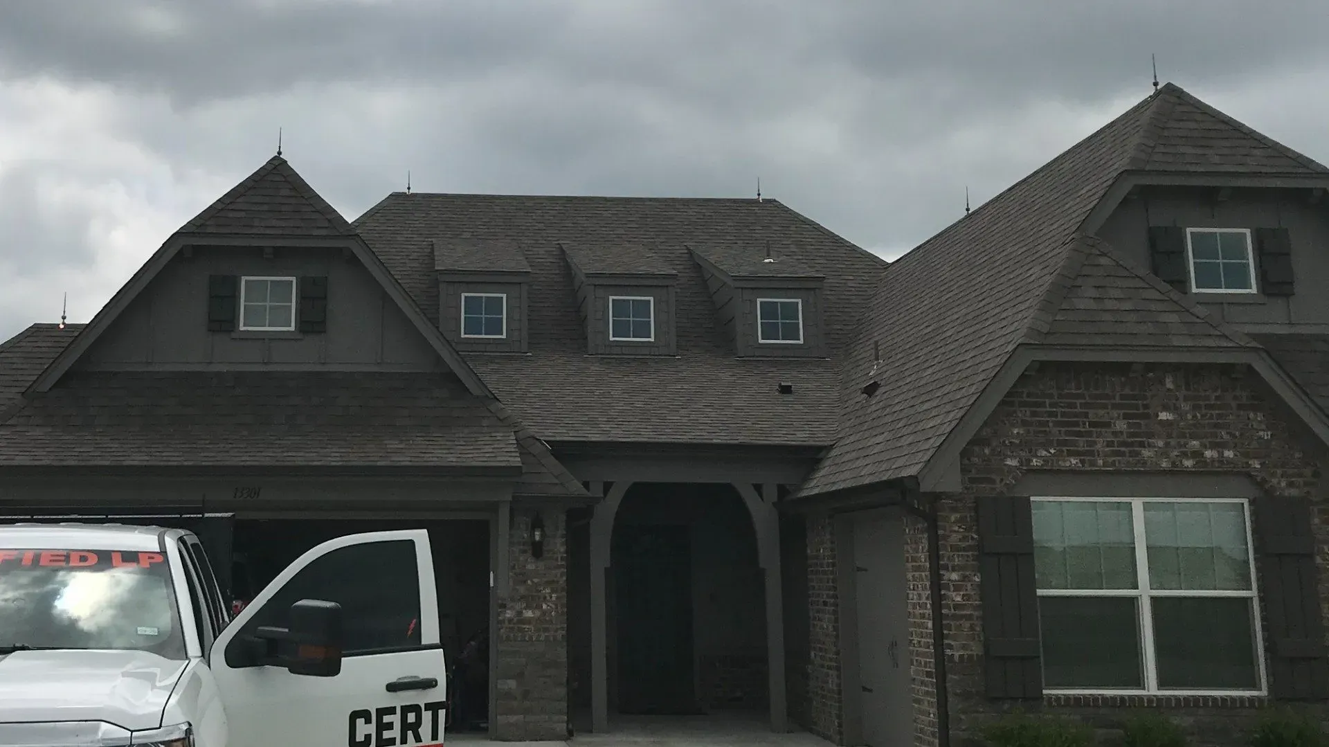 A white truck is parked in front of a large brick house.