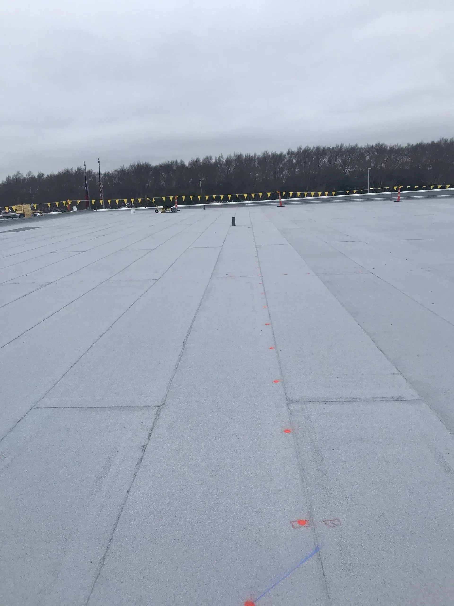 A roof with a lot of snow on it and trees in the background.
