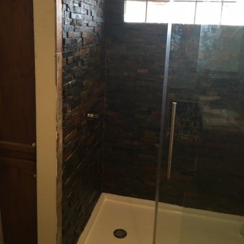 Modern stone tile shower with a glass door enclosure.