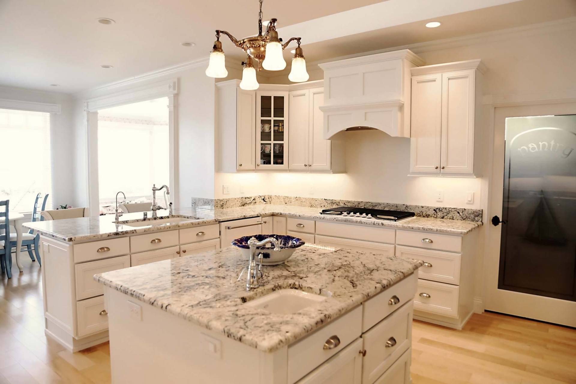 Bright modern white kitchen with granite island, pendant lights, and stainless steel appliances