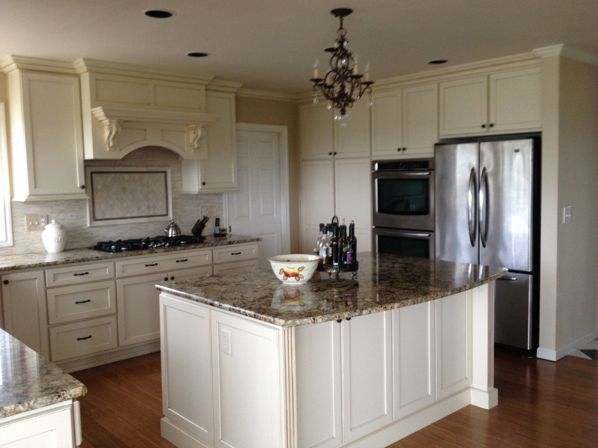 Bright, spacious kitchen with cream cabinets, granite island, stainless steel refrigerator, and hardwood floors