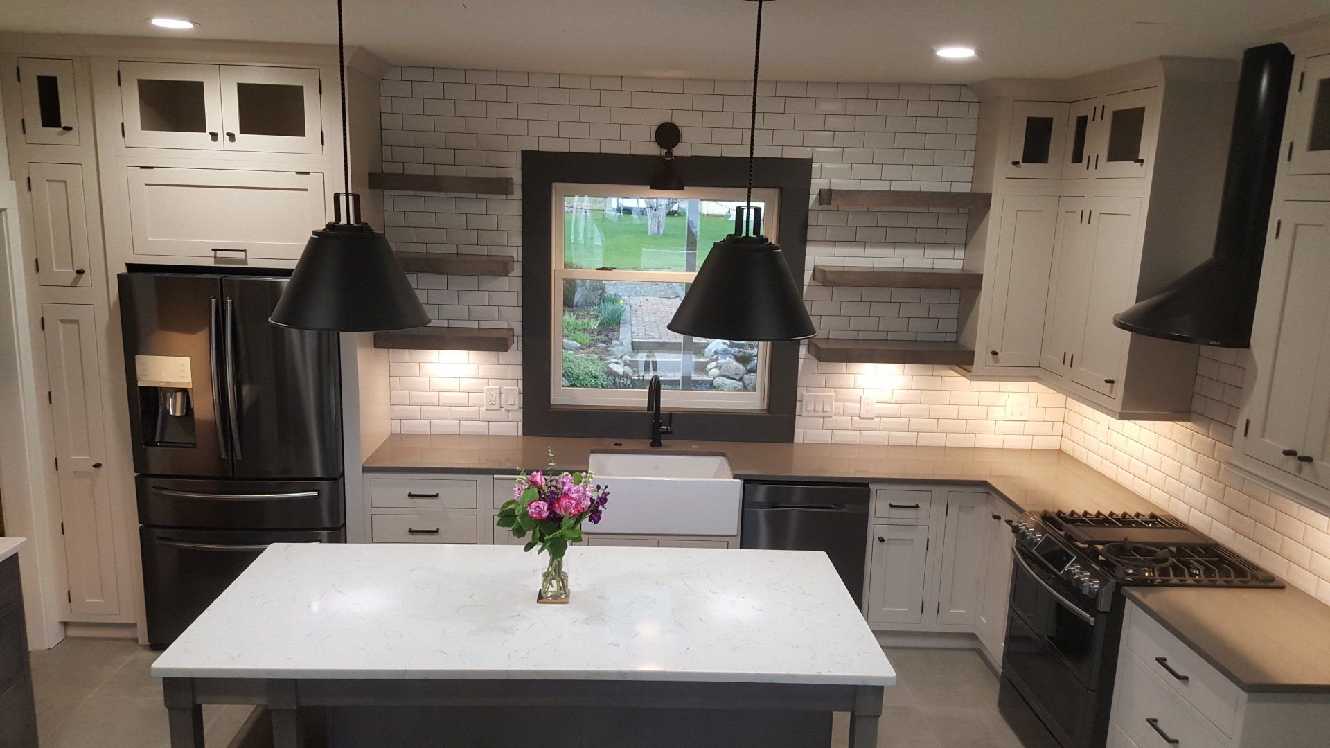 Bright kitchen with white cabinets, large island, pendant lights, and a window over the sink.