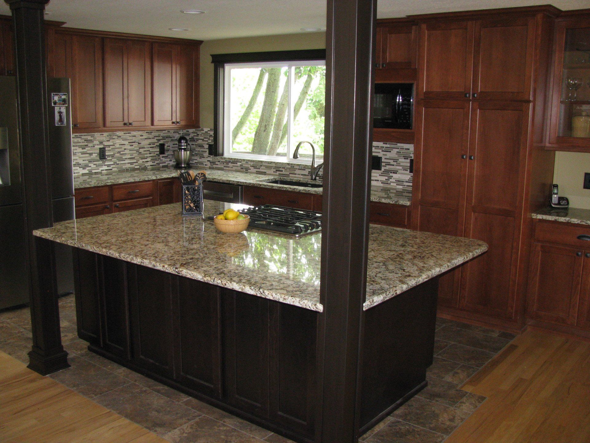 Modern kitchen with dark wood cabinets, granite island, and a window above the sink