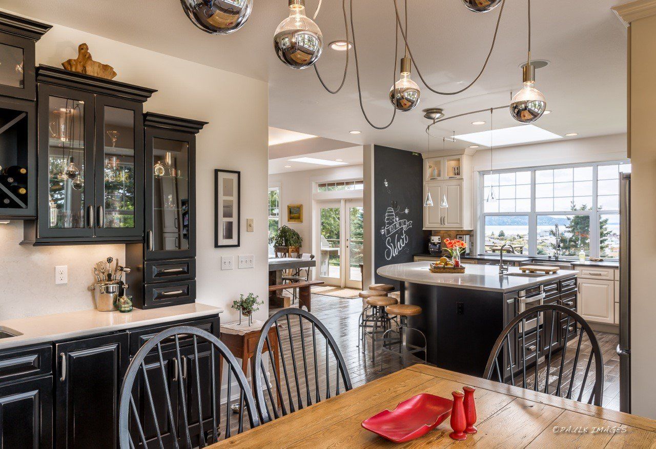 Modern kitchen with black cabinets, island, pendant lights, and wood dining table
