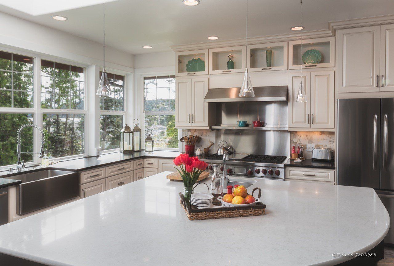 Bright modern kitchen with white cabinets, large island, and fruit centerpiece by sunlit windows