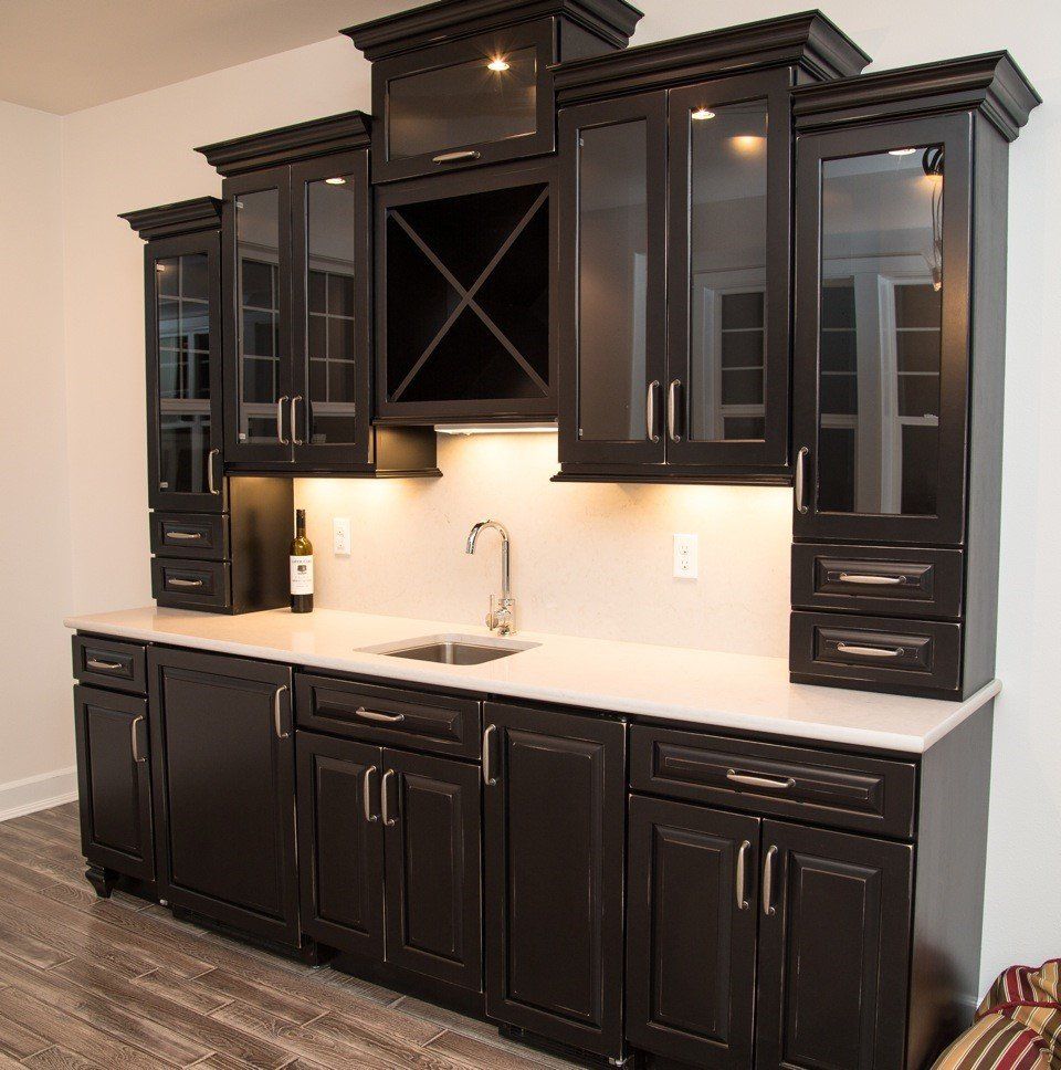 Dark wood kitchen cabinets with glass fronts and white countertop against a white wall