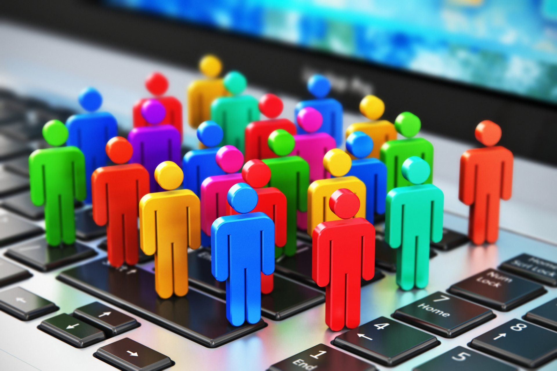 Colorful 3D figures standing on a laptop keyboard, symbolizing online networking or digital community