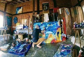 Um homem está ajoelhado em frente a uma grande pintura em uma sala.