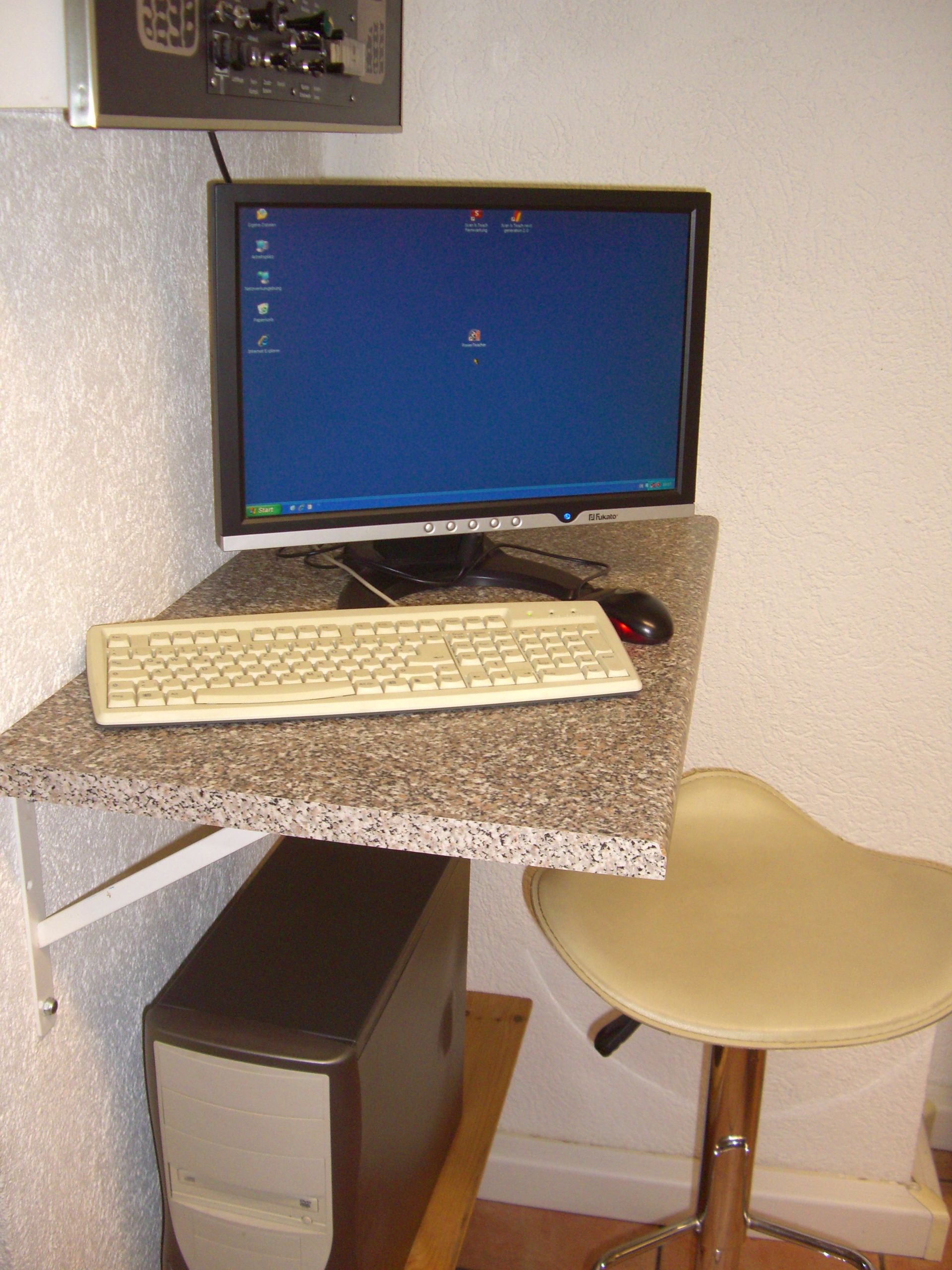 Ein Schreibtisch mit einem Computermonitor, einer Tastatur und einer Maus darauf
