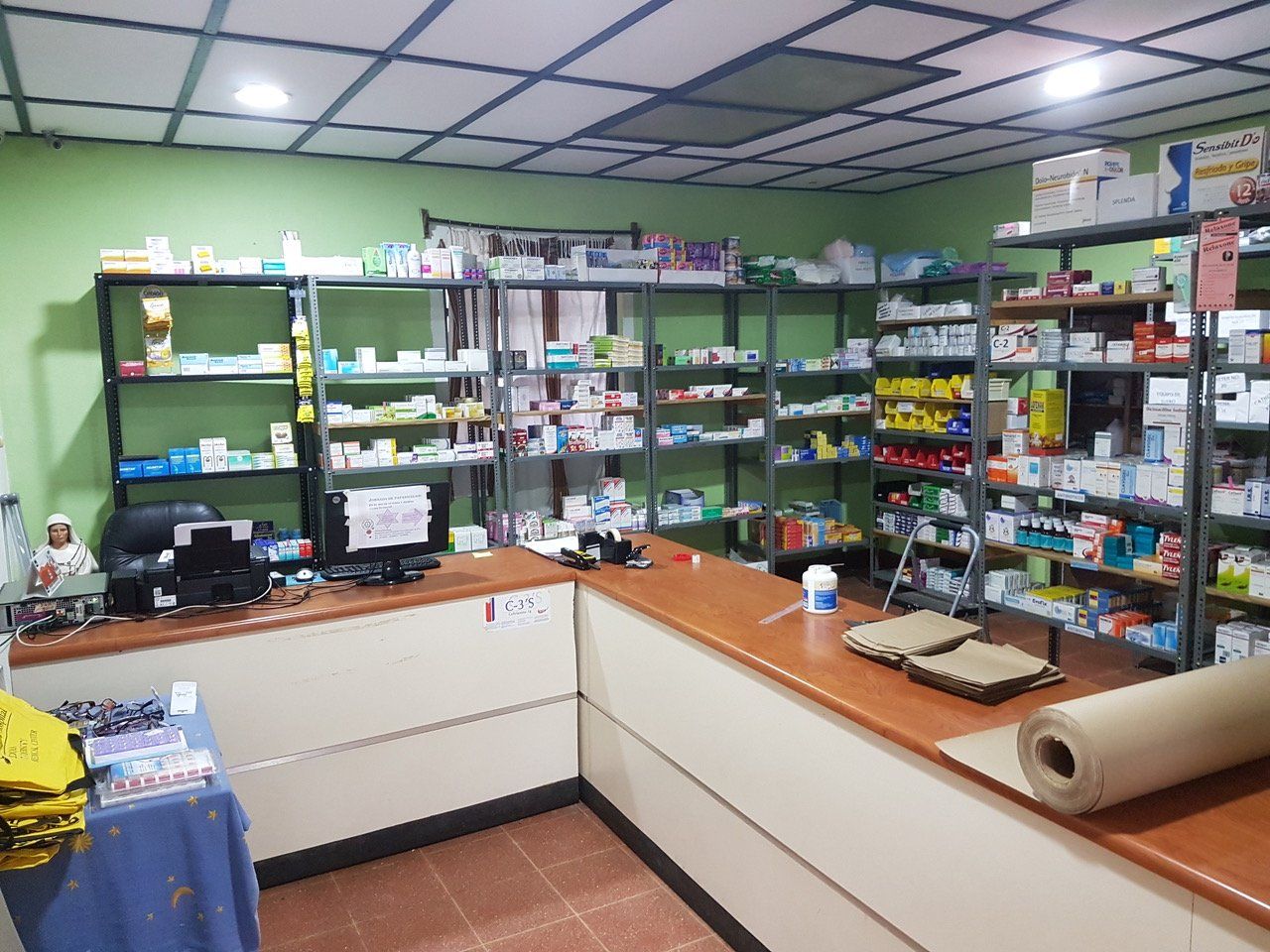 Innenansicht einer Apotheke mit Regalen voller Medikamente und einem Tresen.