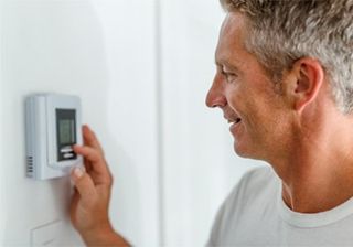 About — Smiling Man Adjusting Thermostat on Home Heating System in Andover, NJ About — Smiling Man Adjusting Thermostat on Home Heating System in Andover, NJ