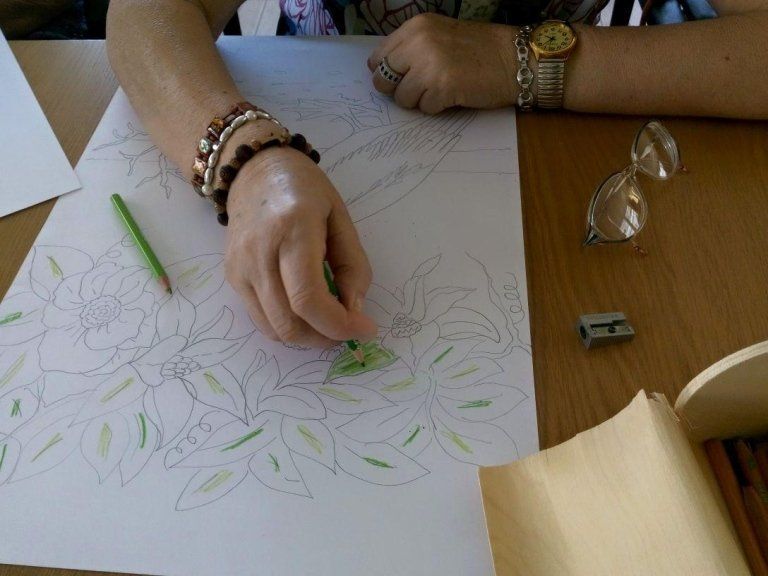 una donna anziana che colora con pastello