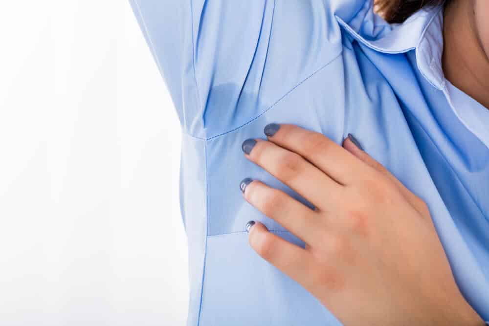 Uma mulher de camisa azul está segurando a axila.