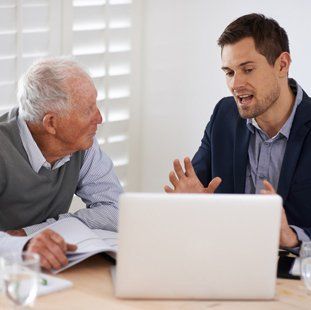 A solicitor talking to an older client, with a white laptop in front of him