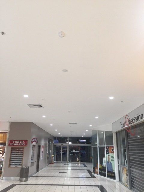 Empty indoor mall corridor with closed storefronts and bright ceiling lights