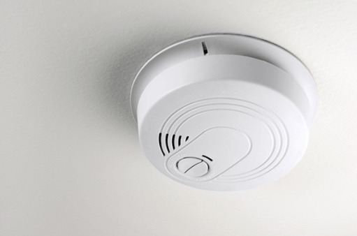 White smoke detector mounted on a ceiling, close-up view.