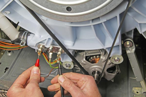 Hands using red and black probes to test wiring inside a household appliance