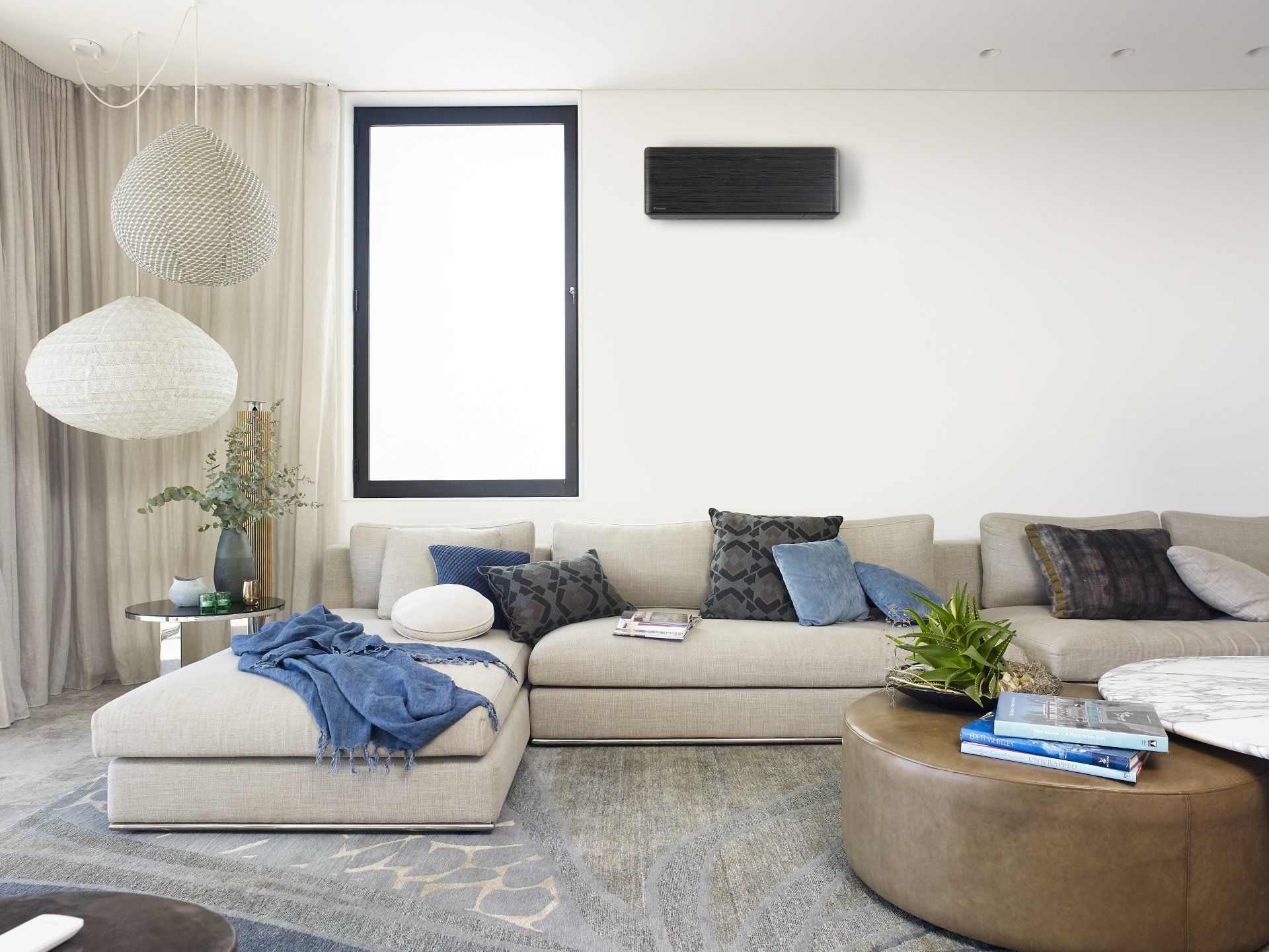 Bright modern living room with beige sectional, round coffee table, pendant lights, and blue accents
