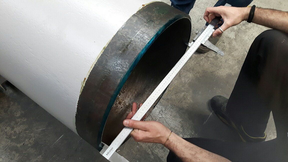 Un uomo sta misurando un tubo di metallo con un calibro.