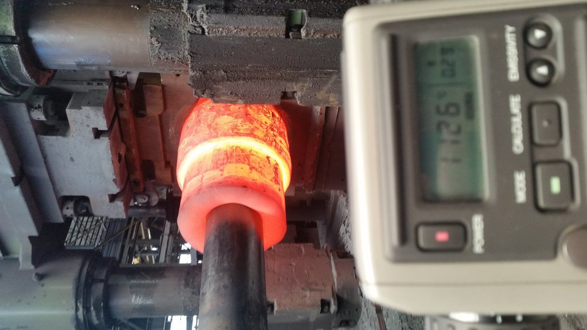 Un termometro digitale è posizionato accanto a un oggetto metallico caldo.