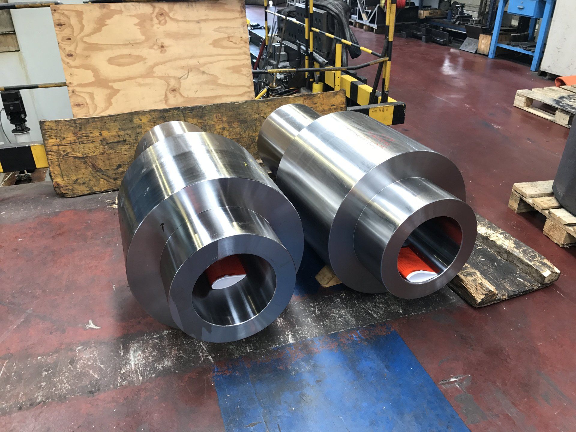 Due grandi cilindri metallici sono appoggiati su un tavolo in una fabbrica.