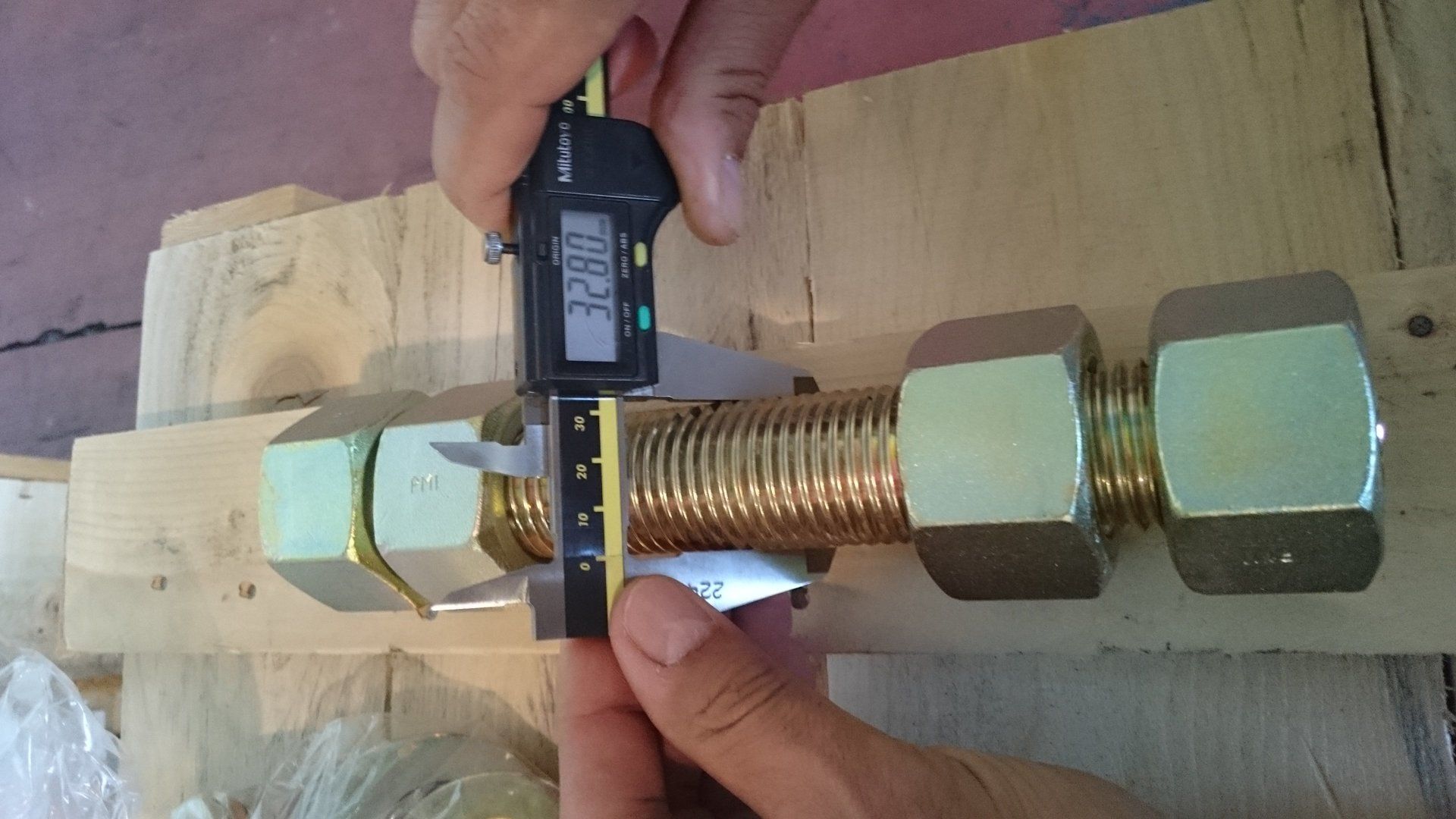 Una persona sta misurando un bullone con un calibro digitale.