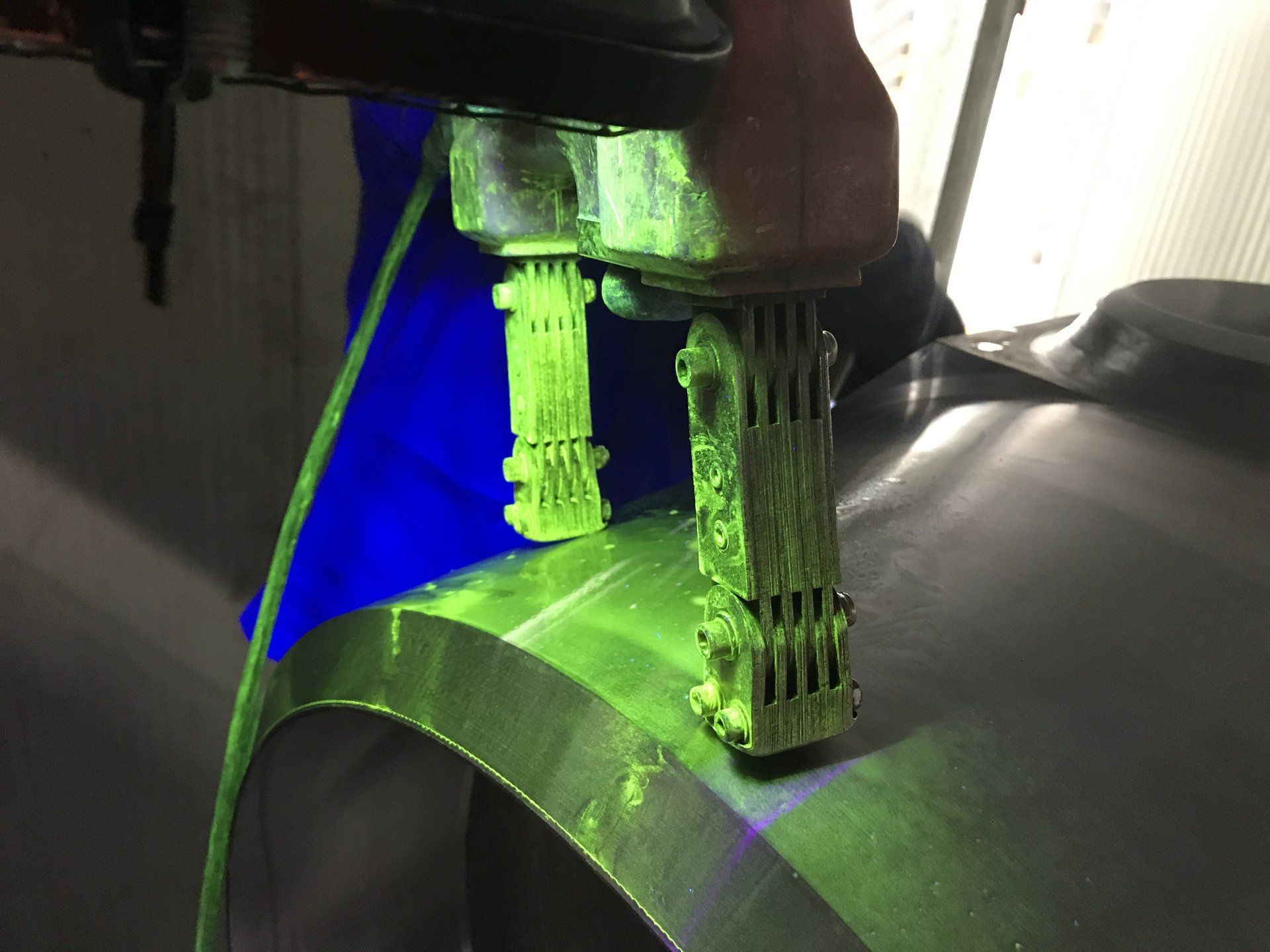 Una persona sta lavorando su un pezzo di metallo illuminato da una luce verde.