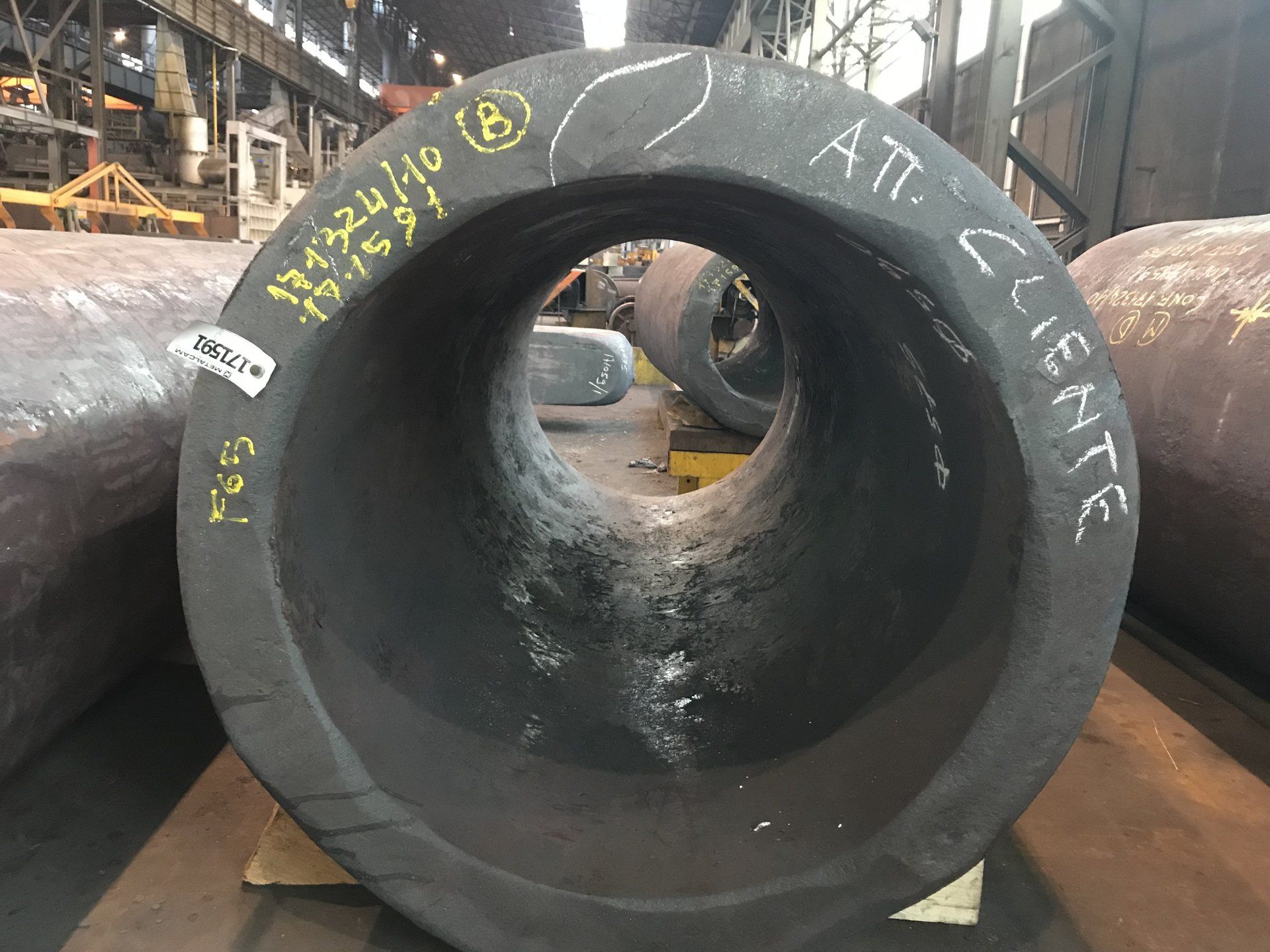 Un grande tubo di metallo è appoggiato su un tavolo in una fabbrica.