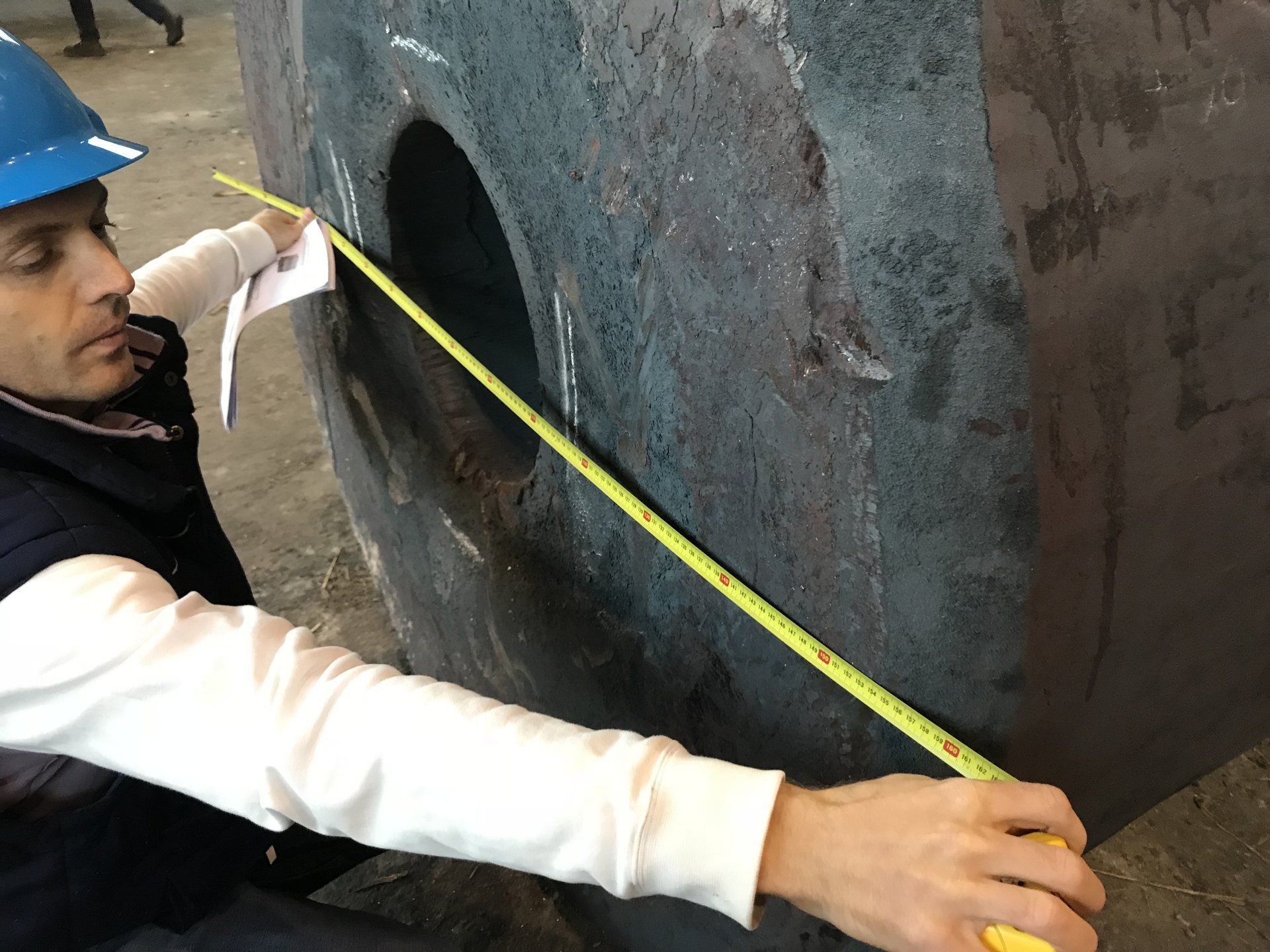 Un uomo sta misurando un buco nel muro con un metro a nastro.