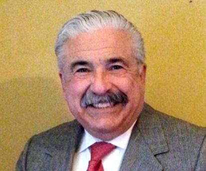 A man with a mustache is wearing a suit and tie and smiling.