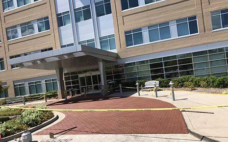Exterior of a multi-story building with a covered entrance. Yellow caution tape surrounds the walkway.