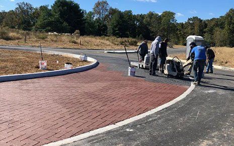Construction workers applying red surface coating to new curved pavement.