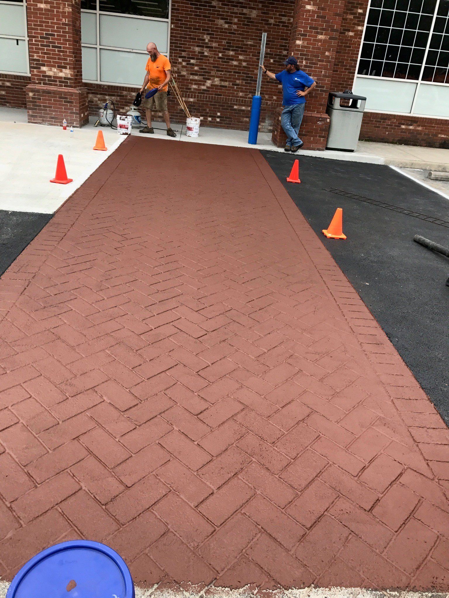 Brick pathway under construction with workers and cones.