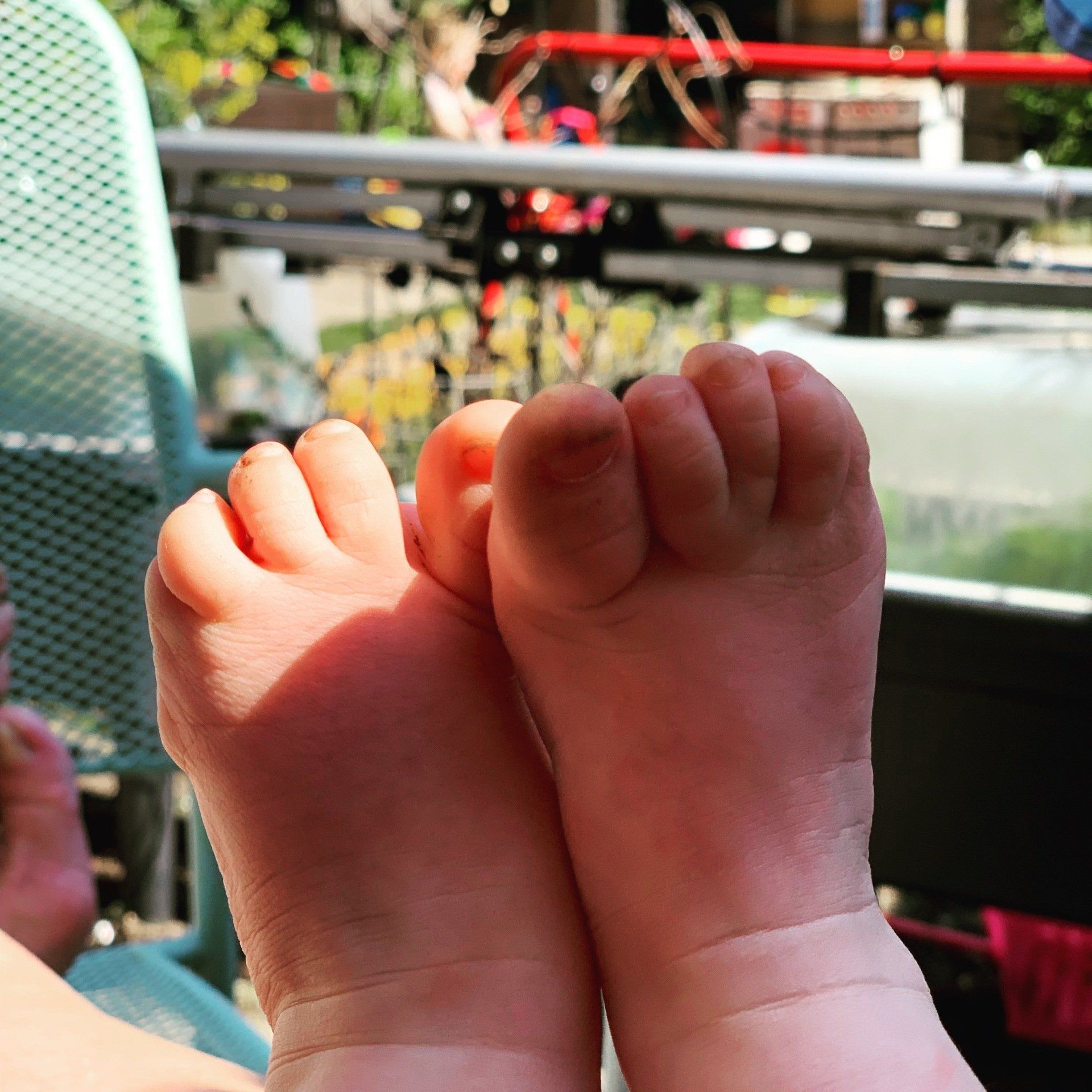 Roze babyvoetjes met opgetrokken tenen in het zonlicht. 