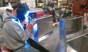 A man is welding a piece of metal on a table.