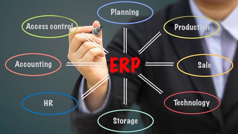 A person in a suit writing on a virtual diagram of ERP systems with various business functions.