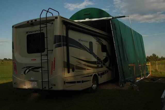 A rv is parked in a field with the door open
