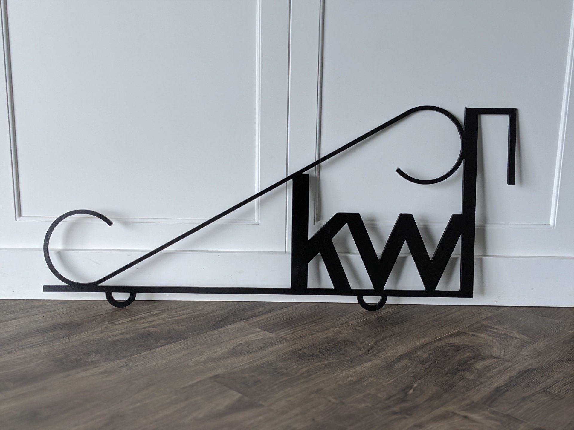 A sign that says kw is sitting on a wooden floor