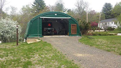 A green garage with a car parked inside of it.