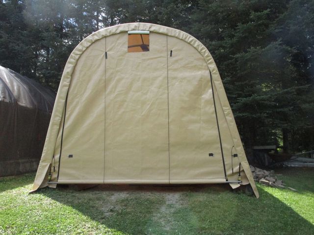 A tan tent is sitting on top of a lush green field